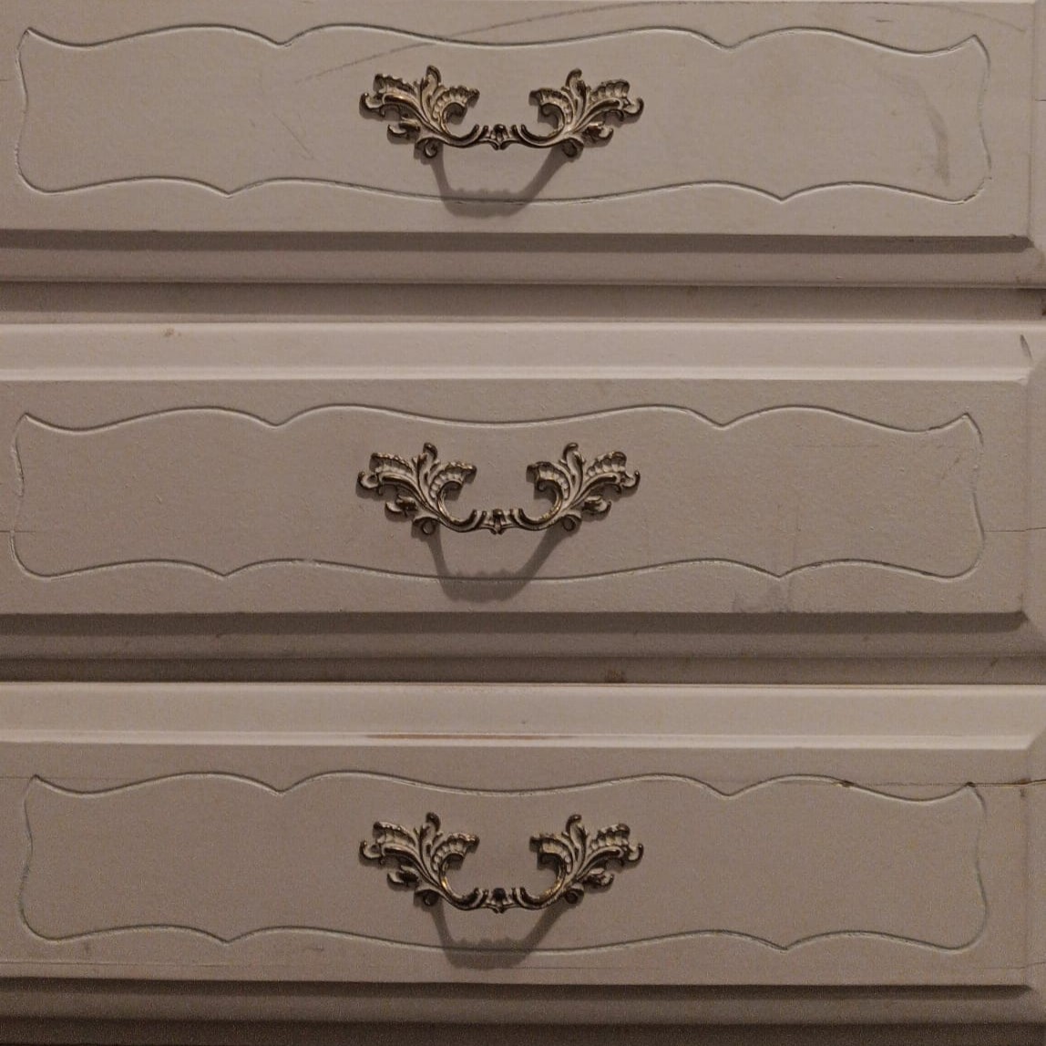A set of drawers with handles that afford pulling outward to access storage.