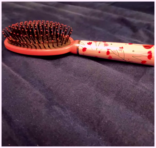 A pink hairbrush laying upright. I added a purple tint effect.