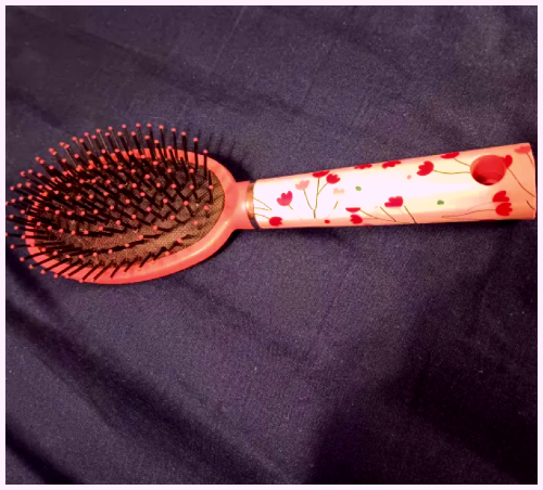 A pink hairbrush laying upright. I added a purple tint effect. This picture was taken at a different angle focusing on the top of the brush.